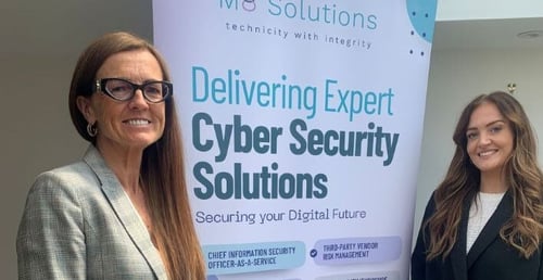 Tracy and Milly next to the cyber security solutions banner